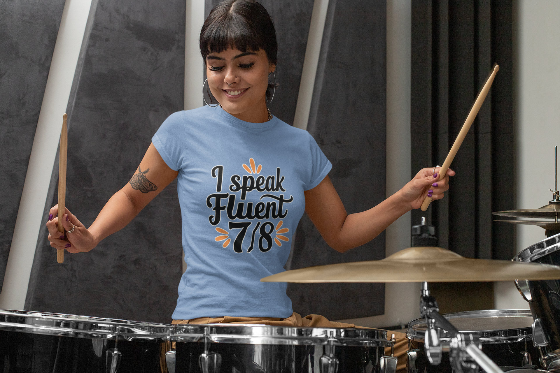 Woman playing drums wearing a blue t-shirt with text
