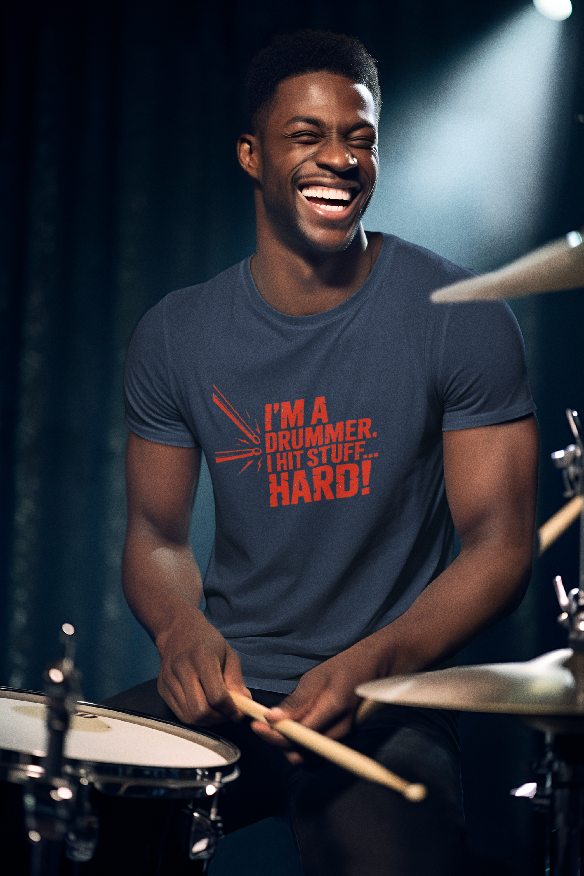 Man playing drums with a shirt that says 'I'm a drummer, I hit stuff hard' on a dark background.